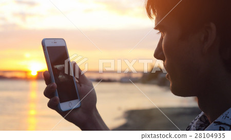 Man uses smart phone at beautiful sunset on the 28104935