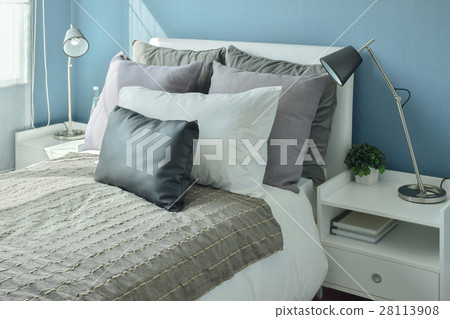 Gray and beige pillows on bed with blue wall 28113908