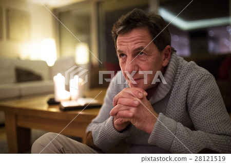 Senior man at home praying, burning candles behind Senior man at home praying, burning candles behind 28121519