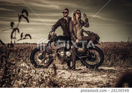 Young, stylish cafe racer couple on vintage custom 28130549