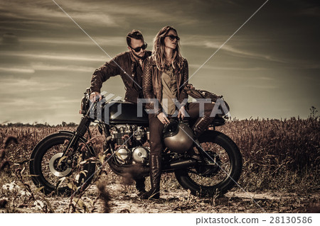 Young, stylish cafe racer couple on vintage custom 28130586