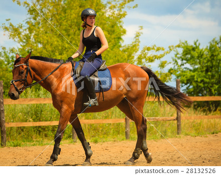 Jockey girl doing horse riding on countryside meadow 28132526