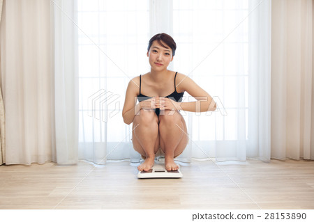 A young woman crouching on a scale 28153890