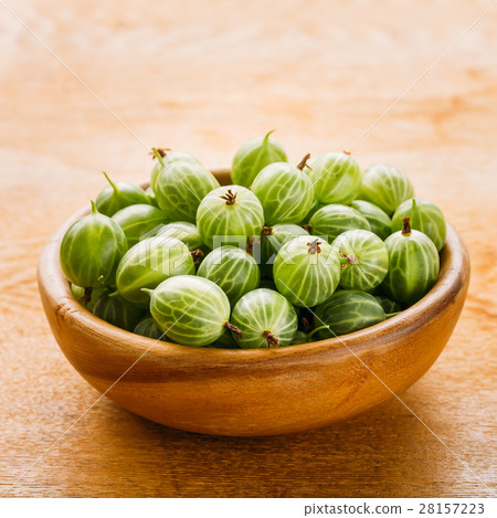 图库照片: close-up of gooseberries in vintage wooden bowl on