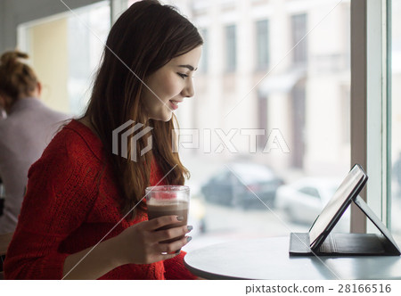 Young girl looking at tablet and smiling in cafe  28166516
