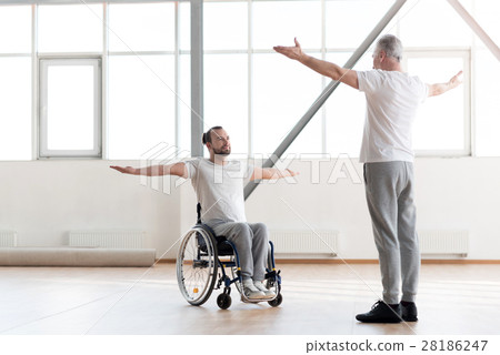 Handsome disabled man training in the gym with the Handsome disabled man training in the gym with the 28186247