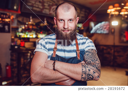 Bearded barman with tattoos wearing an apron Bearded barman with tattoos wearing an apron 28191672