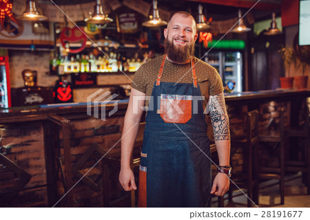 Bearded barman with tattoos and watches wearing an Bearded barman with tattoos and watches wearing an 28191677
