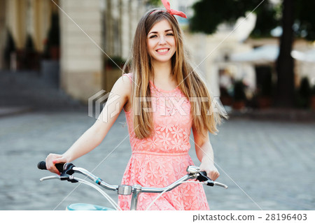 blond-brown girl smiling and holding bicycle. blond-brown girl smiling and holding bicycle. 28196403