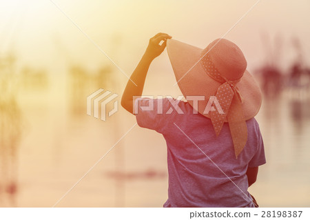 Backside of woman with big hat on the bridge and sunrise Backside of woman with big hat on the bridge and sunrise 28198387