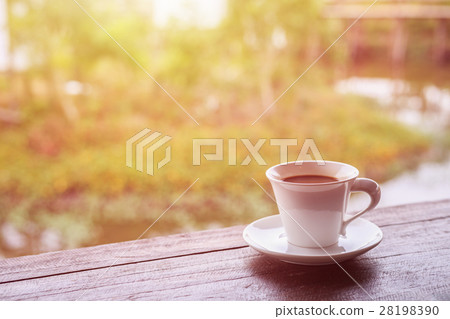 White coffee cup on table in garden with blur light bokeh White coffee cup on table in garden with blur light bokeh 28198390