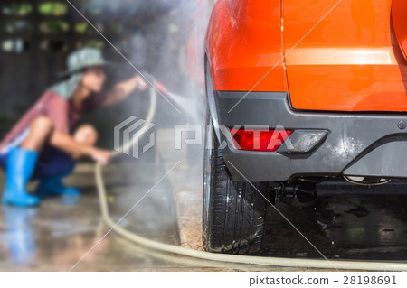 Man spraying pressure washer for car wash in car care shop. Focus on car Man spraying pressure washer for car wash in car care shop. Focus on car 28198691