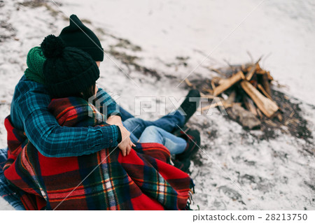 Couple sitting near a bonefire. They are covered Couple sitting near a bonefire. They are covered 28213750