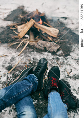 Guy and girl warm feet near a fire 28214169