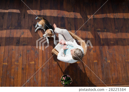 Senior woman with dog, sitting on wooden terrace 28225384