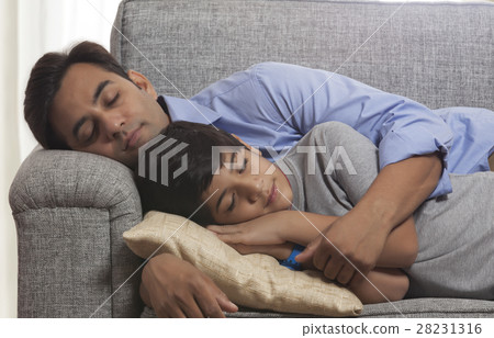 Tired father and son sleeping together on sofa at home 28231316