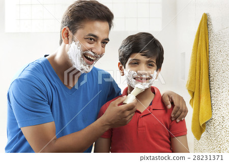 Man applying shaving cream lather on face of his son Man applying shaving cream lather on face of his son 28231371
