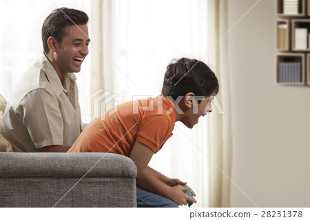 Father playing video game with boy sitting on his shoulder Father playing video game with boy sitting on his shoulder 28231378