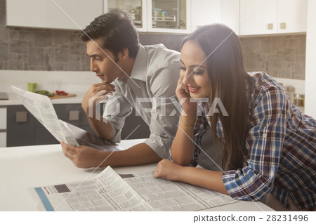 Young couple reading newspaper at kitchen table 28231496