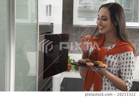 Young woman baking cupcakes in oven Young woman baking cupcakes in oven 28231522