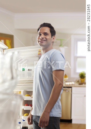 Young man standing in front of open refrigerator Young man standing in front of open refrigerator 28231845