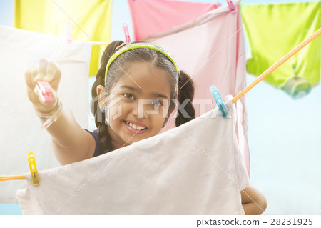 Young girl drying a cloths on a clothesline Young girl drying a cloths on a clothesline 28231925