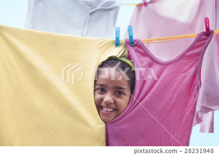 Young girl peeking through cloths on a clothesline Young girl peeking through cloths on a clothesline 28231948