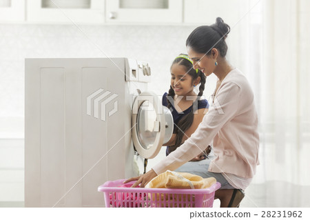 Mother and daughter loading washing machine Mother and daughter loading washing machine 28231962