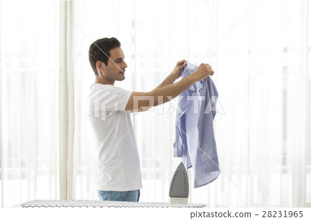 Young man looking at shirt with ironing board in front 28231965