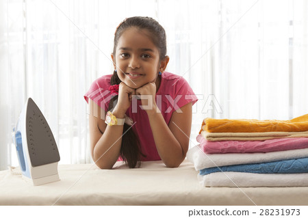 Smiling girl leaning on ironing board with hands on chin Smiling girl leaning on ironing board with hands on chin 28231973