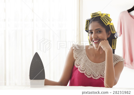 Young woman with hair curlers holding iron appliance  28231982