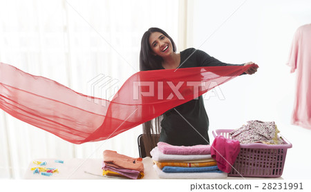 Young woman folding red Dupatta and laundry Young woman folding red Dupatta and laundry 28231991