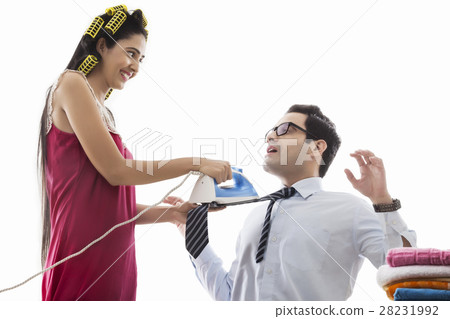 Young woman with curlers ironing man's tie 28231992