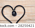 Medical stethoscope in a heart shape on wood table 28250421