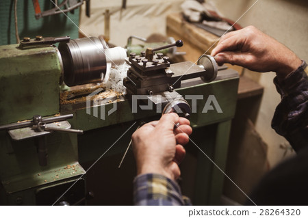 Man makes wood detail on lathe 28264320