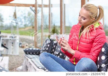 Attractive young blonde woman typing on phone on terrace . Sunny 28264745