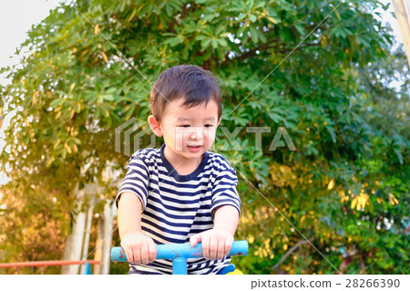Asian kid riding seesaw board at the playground Asian kid riding seesaw board at the playground 28266390