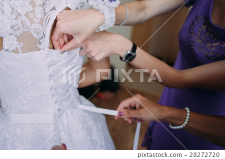 bridesmaid tying bow on wedding dress bridesmaid tying bow on wedding dress 28272720