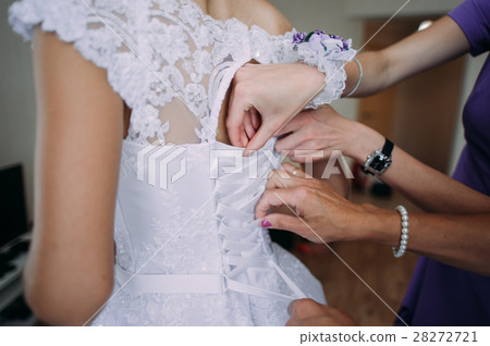 bridesmaid tying bow on wedding dress bridesmaid tying bow on wedding dress 28272721