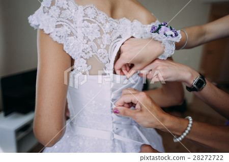 bridesmaid tying bow on wedding dress bridesmaid tying bow on wedding dress 28272722