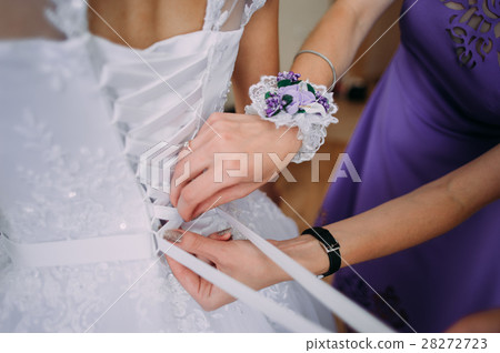 bridesmaid tying bow on wedding dress bridesmaid tying bow on wedding dress 28272723