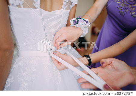 bridesmaid tying bow on wedding dress bridesmaid tying bow on wedding dress 28272724