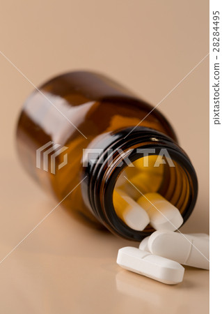 Brown glass pill bottle and white pills Brown glass pill bottle and white pills 28284495