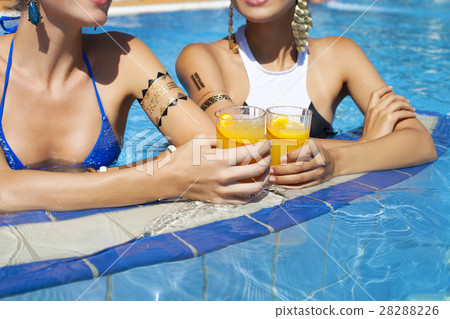Women drinking a cocktails relaxing by pool Women drinking a cocktails relaxing by pool 28288226