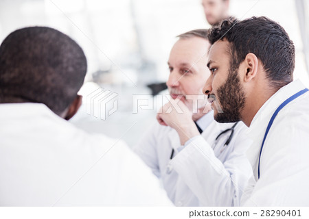 Serene bearded physician hearing colleagues during 28290401