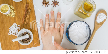 Woman is applying homemade cream on hand. 28303185