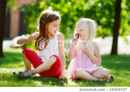 Adorable little girls playing with paper moustaches on a stick and other accessories Adorable little girls playing with paper moustaches on a stick and other accessories 28308597
