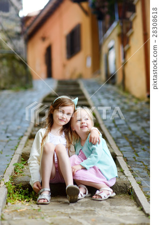 Two adorable little sisters laughing and hugging each other on warm and sunny summer day 28308618
