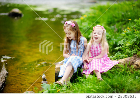 Two adorable little sisters playing by a river in sunny park 28308633