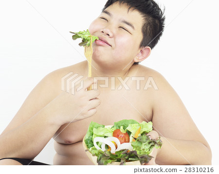 A fat boy is happily eating vegetable salad A fat boy is happily eating vegetable salad 28310216